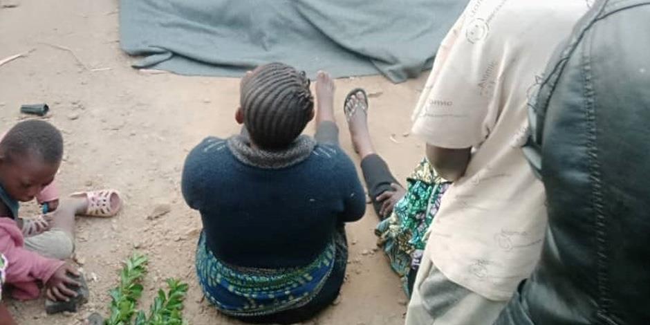 En kvinna sitter utanför ett hus i den drabbade stadsdelen Masosi. Filten framför henne täcker ett av offren i attacken. 