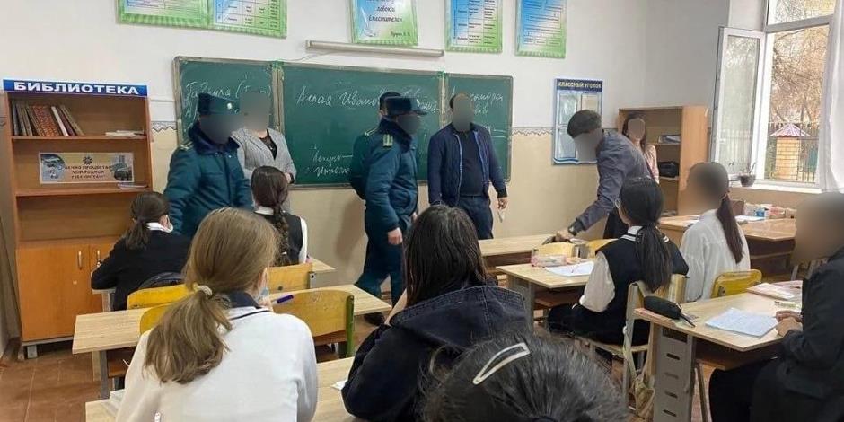 Polis kontrollerar skolelevers mobiltelefoner på en gymnasieskola i Uzbekistan.