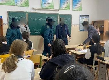 Polis kontrollerar skolelevers mobiltelefoner på en gymnasieskola i Uzbekistan.