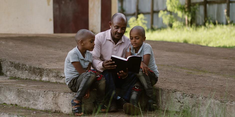 Fasil och Ezana Tedesse läser Bibeln tillsammans med sin pappa Ermias.