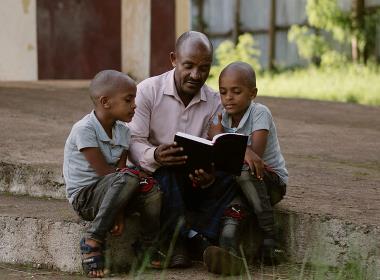 Fasil och Ezana Tedesse läser Bibeln tillsammans med sin pappa Ermias.