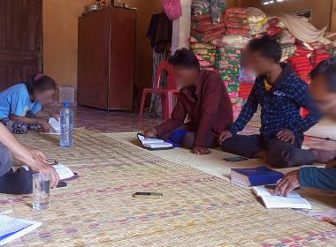 Pastor Phasouk* (längst till höger i bild) läser Bibeln under besöket av Open Doors samarbetspartner Lamthan*.