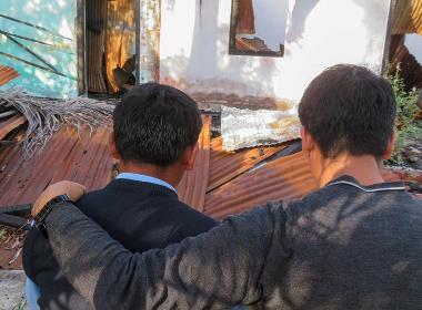 Ajay* (till vänster) utanför sin kyrka, som förstördes under Manipur-upploppen i maj 2023.